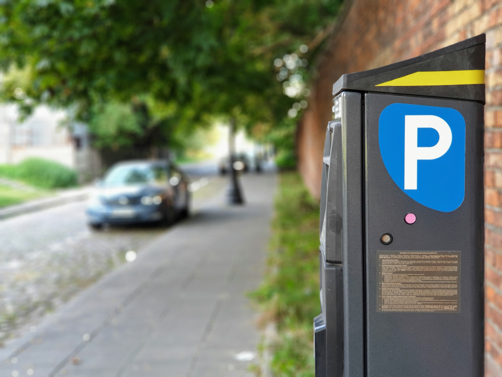 parking meter on sitewalk with a parked car in the background